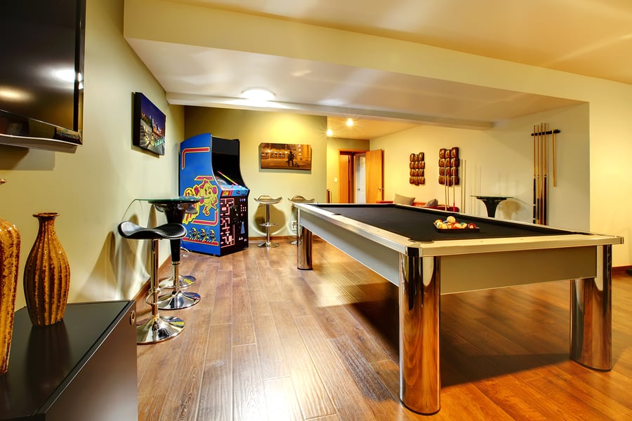 Fun play room home interior. Basement room without windows with pool table TV games.